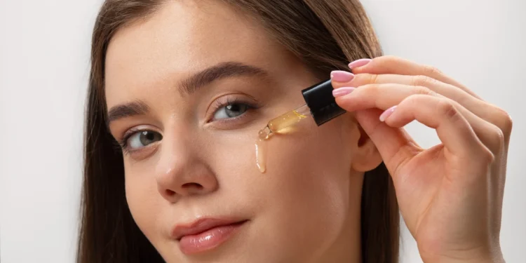 Óleos naturais para a pele e cabelo: veja os mais poderosos e como usar 1 Mulher jovem aplicando óleo de semente de uva na pele, destacando os cuidados com a pele e o uso de produtos naturais.