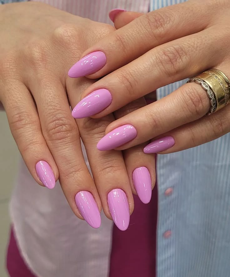 Mãos com unhas longas pintadas com esmalte rosa, segurando uma sobre a outra.