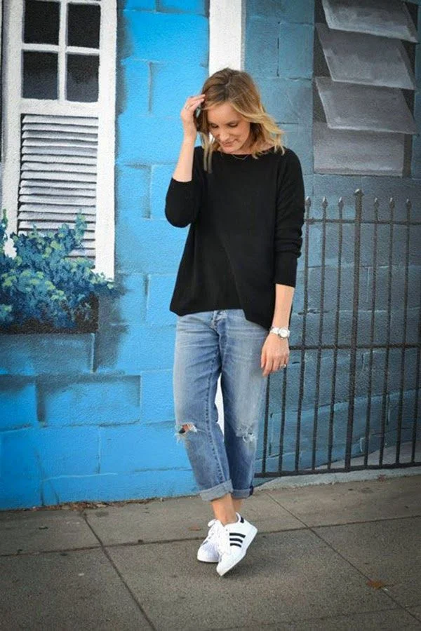 Look estiloso com Adidas Superstar, calça jeans rasgada e blusa preta, estilo casual e moderno.