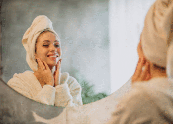 Mulher sorrindo em frente ao espelho com toalha na cabeça