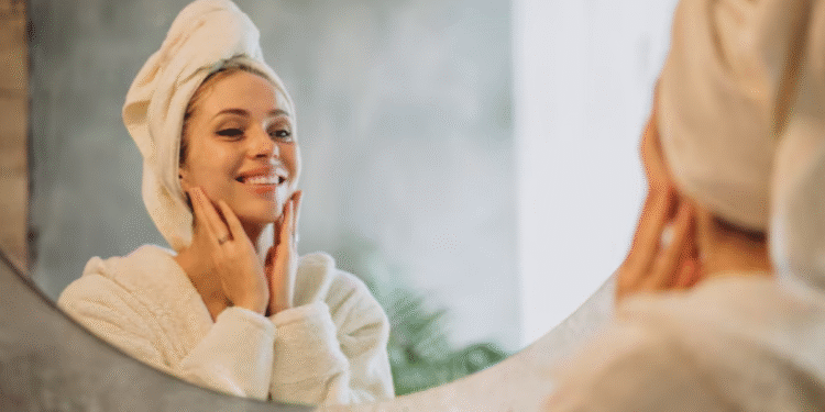 Mulher sorrindo em frente ao espelho com toalha na cabeça
