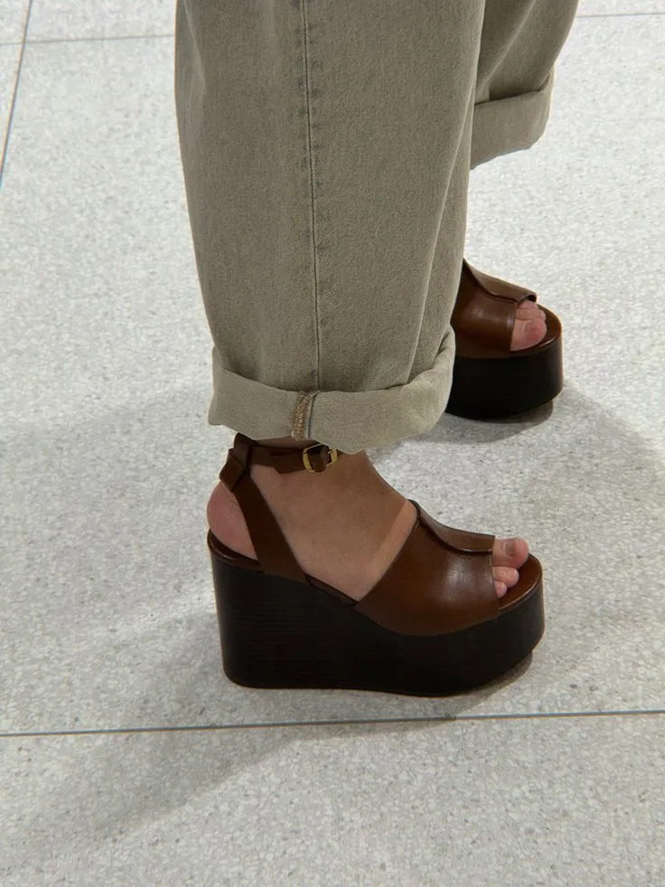 Sapatos de plataforma marrons com salto grosso e tiras, usados com calça bege dobrada