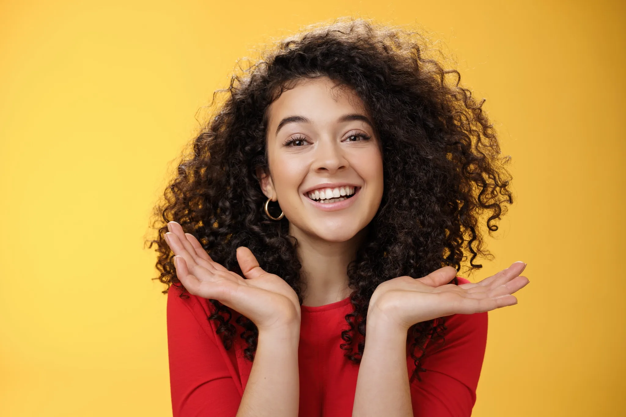 Mulher sorridente com cabelos cacheados volumosos, transmitindo alegria e confiança