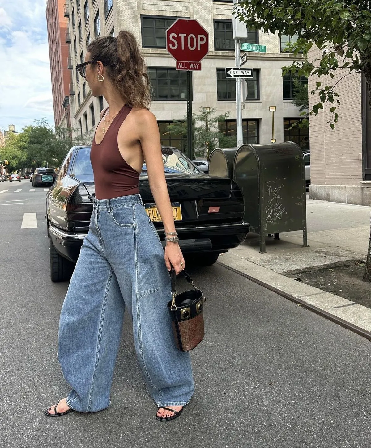 Mulher usando calça balloon com uma regata simples, caminhando na rua com um estilo moderno e descontraído.