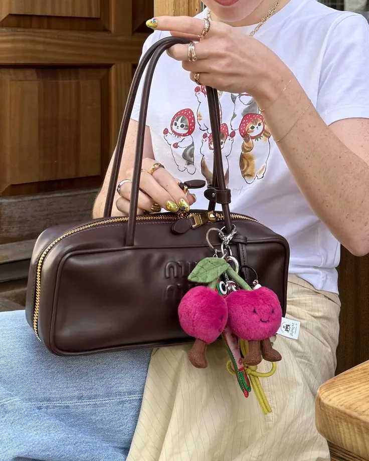 Bolsa marrom com chaveiro de cerejas de pelúcia