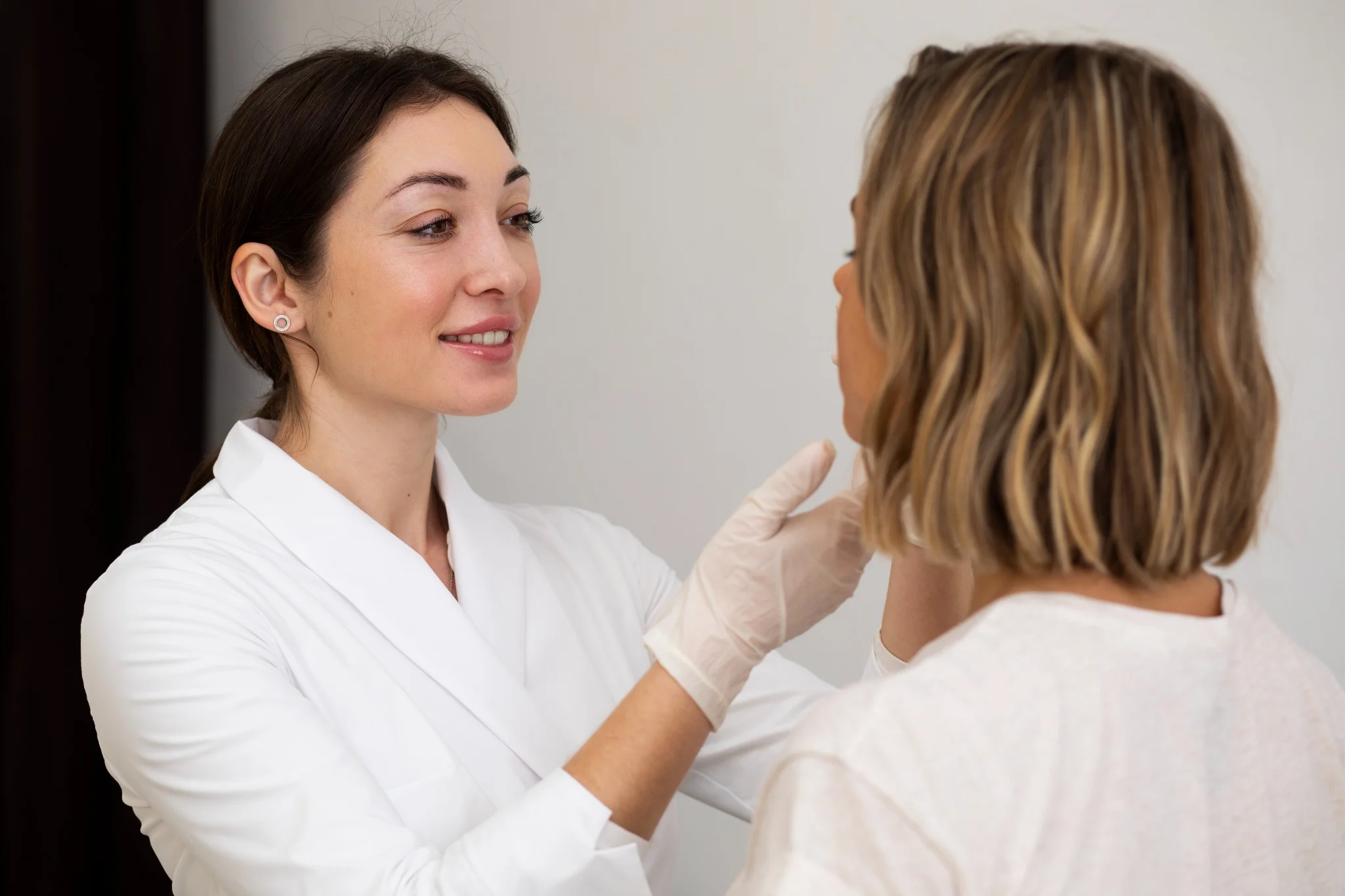 Dermatologista sorridente realizando consulta em paciente durante avaliação facial