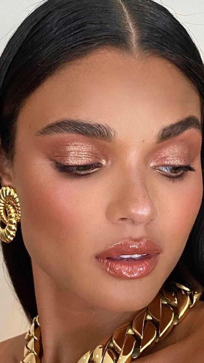 Mulher com maquiagem glow em tons dourados e acabamento luminoso