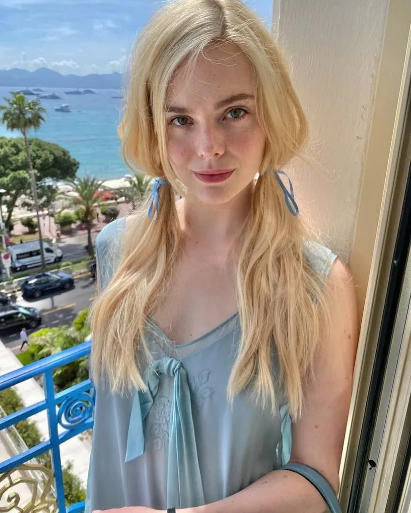 Elle Fanning exibindo cabelo loiro iluminado com tom esverdeado em ambiente ensolarado.