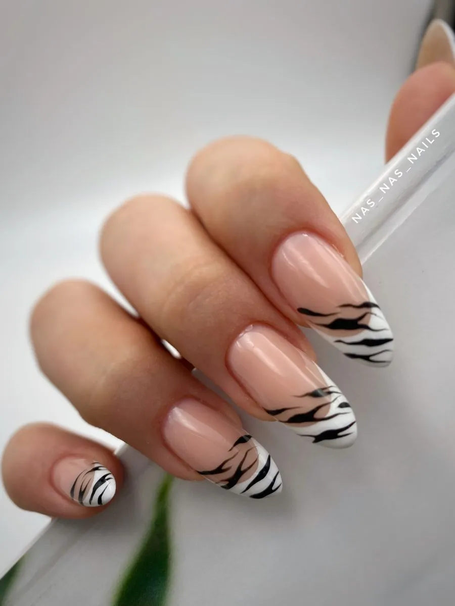 Unhas com estampa de zebra, com listras pretas e fundo branco, criando um visual elegante e ousado.