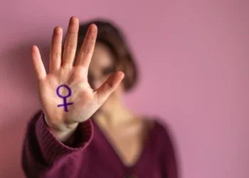 Mulher segurando a mão com o símbolo feminino, em uma reflexão sobre a luta contra o feminicídio.