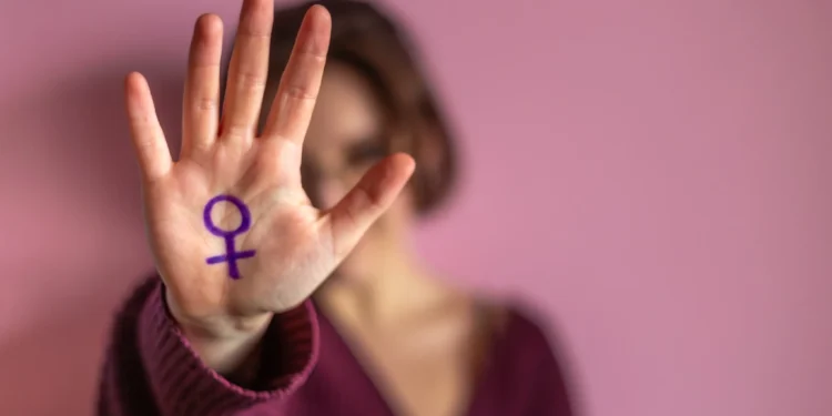 Mulher segurando a mão com o símbolo feminino, em uma reflexão sobre a luta contra o feminicídio.