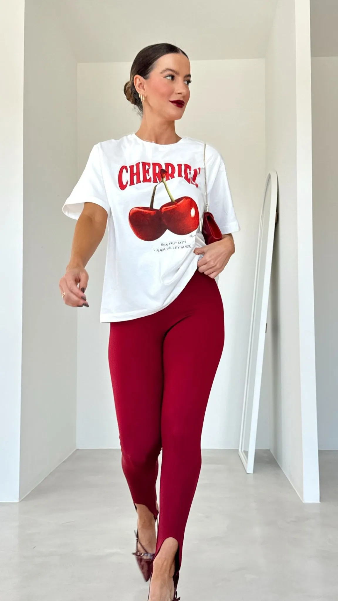 Mulher usando calça legging vermelha e camiseta estampada com ilustração de cerejas