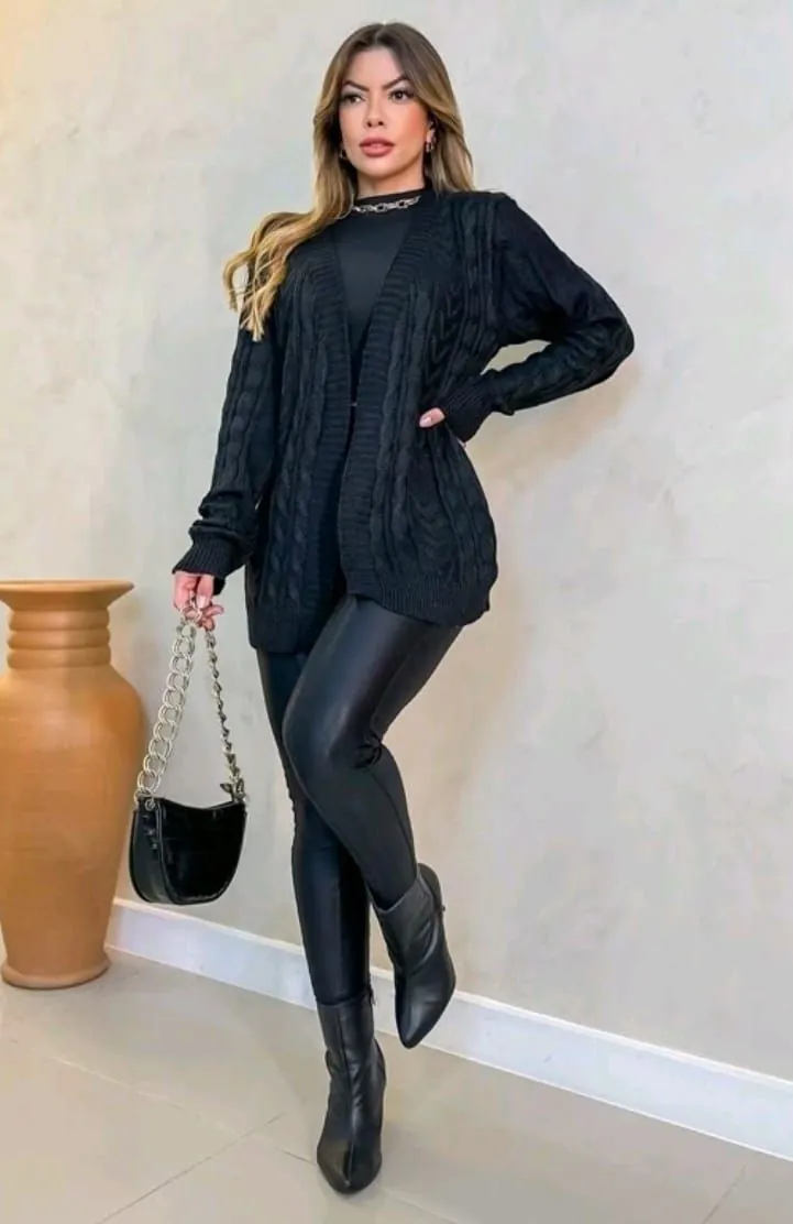 Mulher com look all black, usando tricô, legging e bota de couro