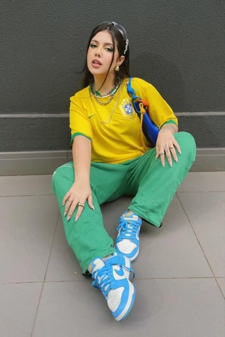 Look vibrante com camisa de time e calça verde, apostando em um visual alegre e moderno.