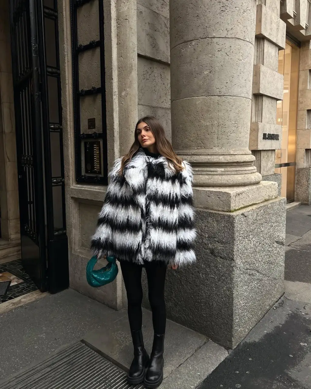 Mulher com casaco de pelos, legging preta e bota chelsea