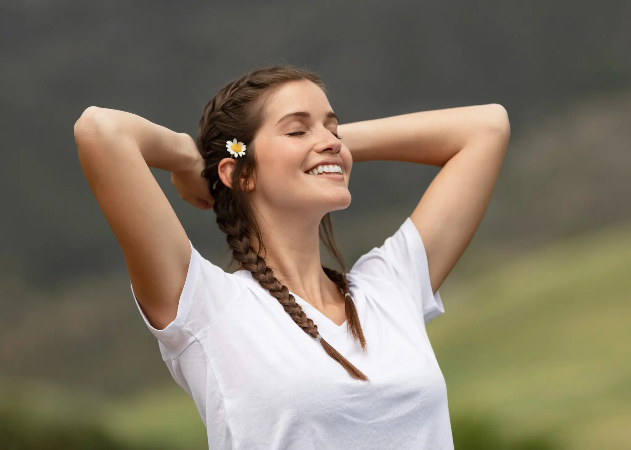 Mulher sorrindo e relaxando ao ar livre com os braços levantados, com autoestima