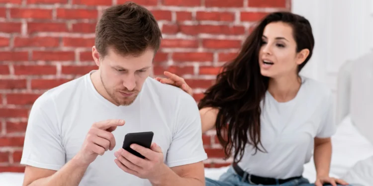 Namoros reais x casais de Instagram: por que estamos tão obcecadas? 1 Mulher tentando chamar a atenção do namorado que está distraído com o celular, refletindo sobre as expectativas em relacionamentos reais versus os casais perfeitos das redes sociais.