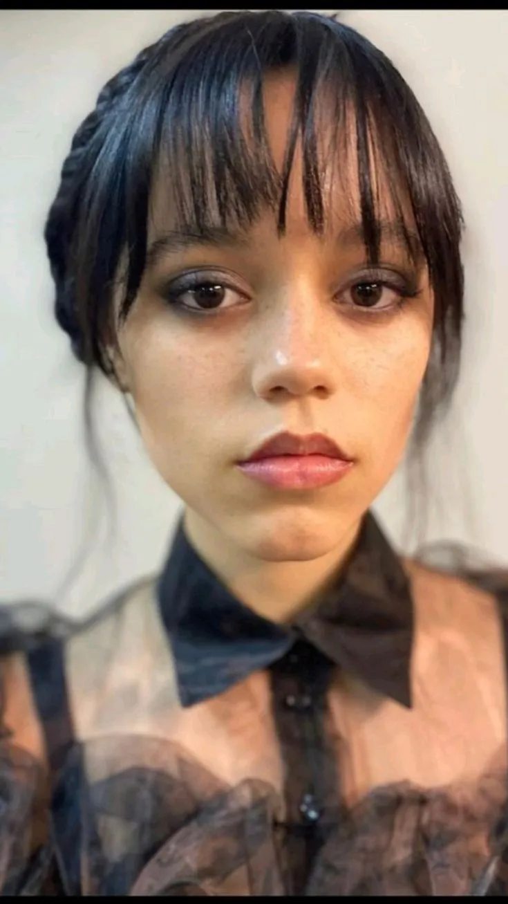 Wandinha Addams, interpretada por Jenna Ortega, com uma expressão séria e maquiagem suave.