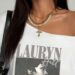 Mulher usando camiseta branca com estampa de Lauryn Hill e ombro caído, estilo anos 2010.