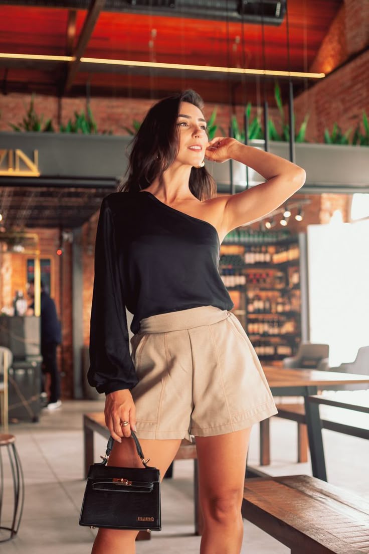 mulher usando uma blusa preta de um ombro só e bermuda oversized