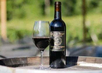 Garrafas e taça de Cabernet Sauvignon da Cellar Beast Winehouse com fundo natural de vinhedo.