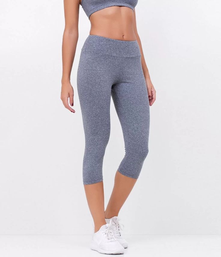 Mulher vestindo calça corsário cinza, top esportivo e tênis branco.