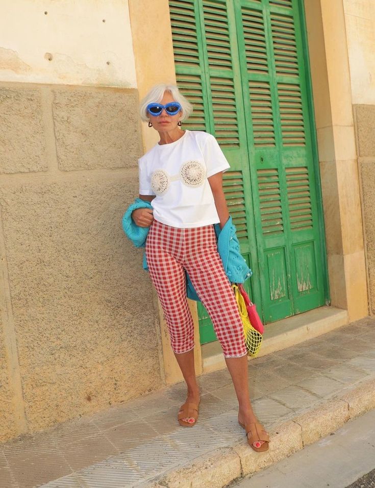 Pessoa vestindo calça corsário xadrez, camiseta branca estampada e jaqueta azul, em um look com mix de estampas.