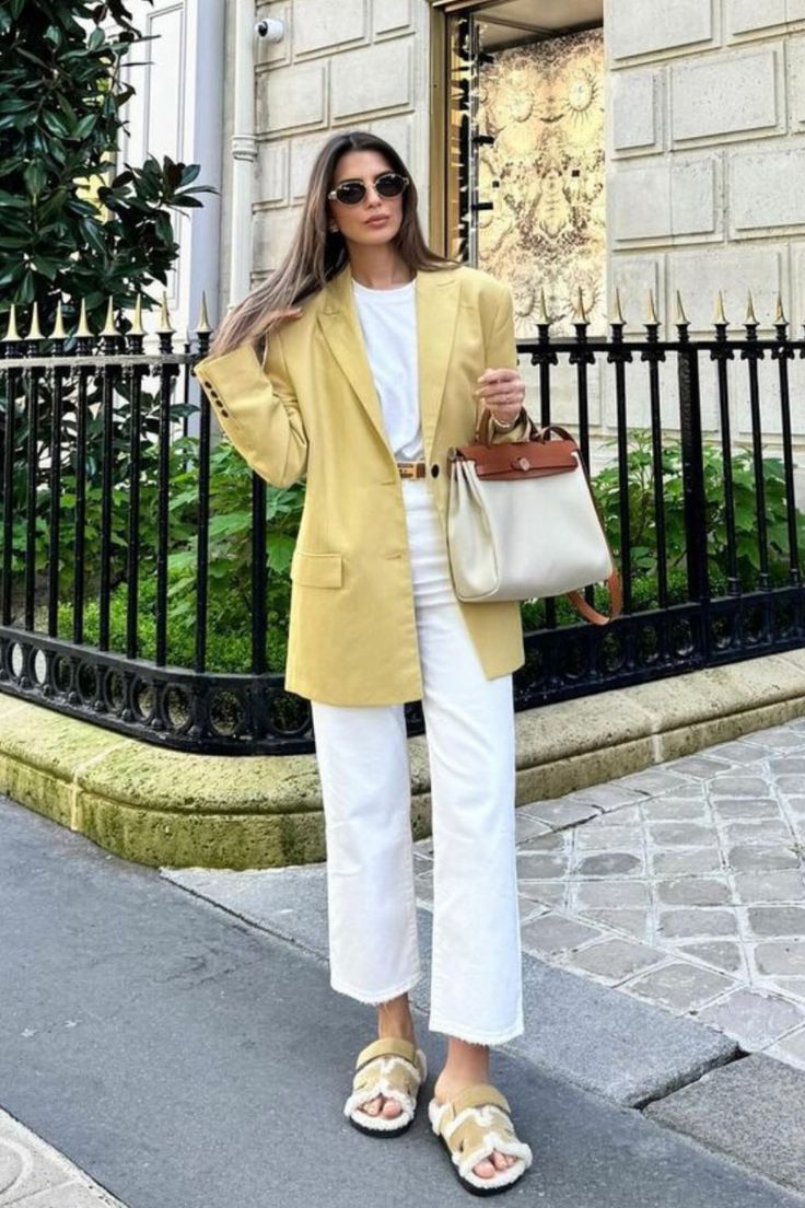 Mulher usando um blazer amarelo-manteiga combinado com calça branca, mostrando uma forma elegante de usar a cor.