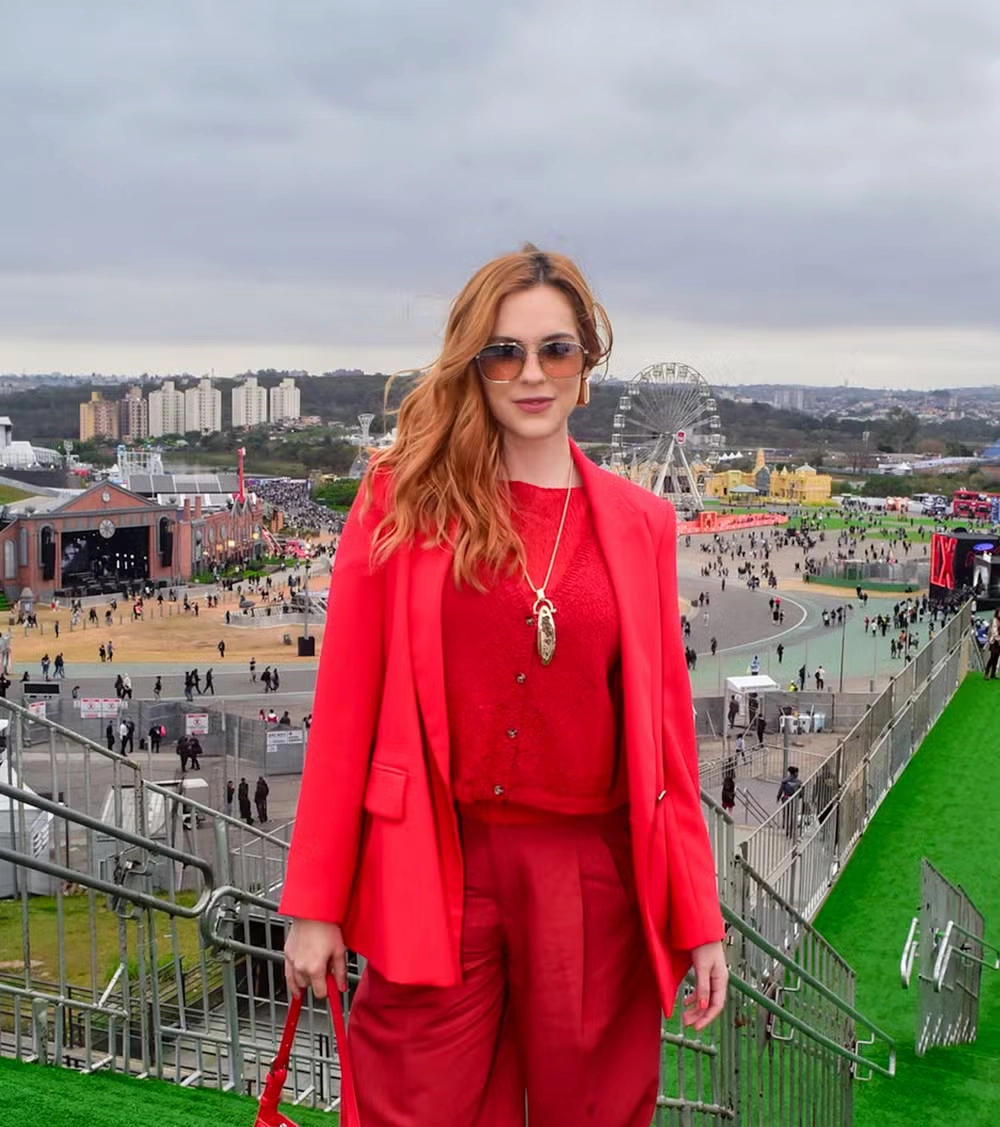 Sophia Abrahão em look monocromático vermelho no The Town 2025, com blusa e calça combinando, usando óculos de sol e sorrindo para a câmera.