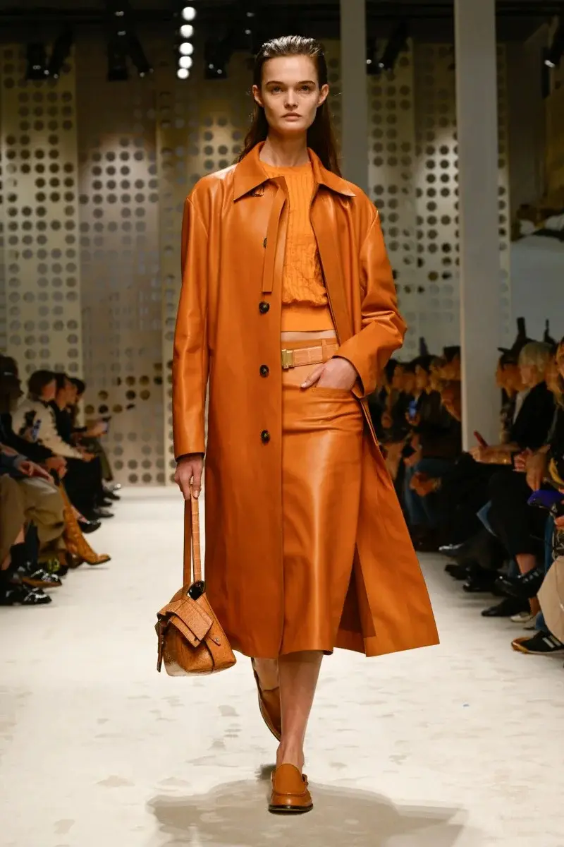 Modelo desfilando com visual monocromático em tons de laranja na temporada SS26