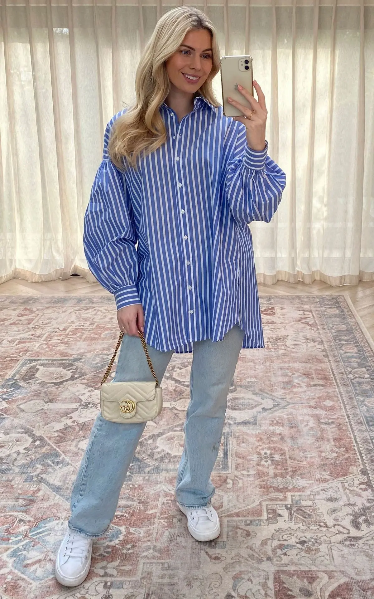 Mulher sorrindo em um look casual com camisa listrada azul e branca