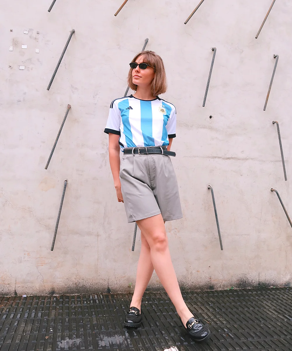 Mulher com camisa de time e shorts de cintura alta em look casual