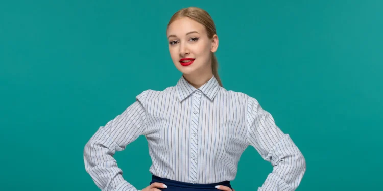 Mulher com camisa listrada, pose confiante com fundo verde, mostrando estilo de primavera e verão.