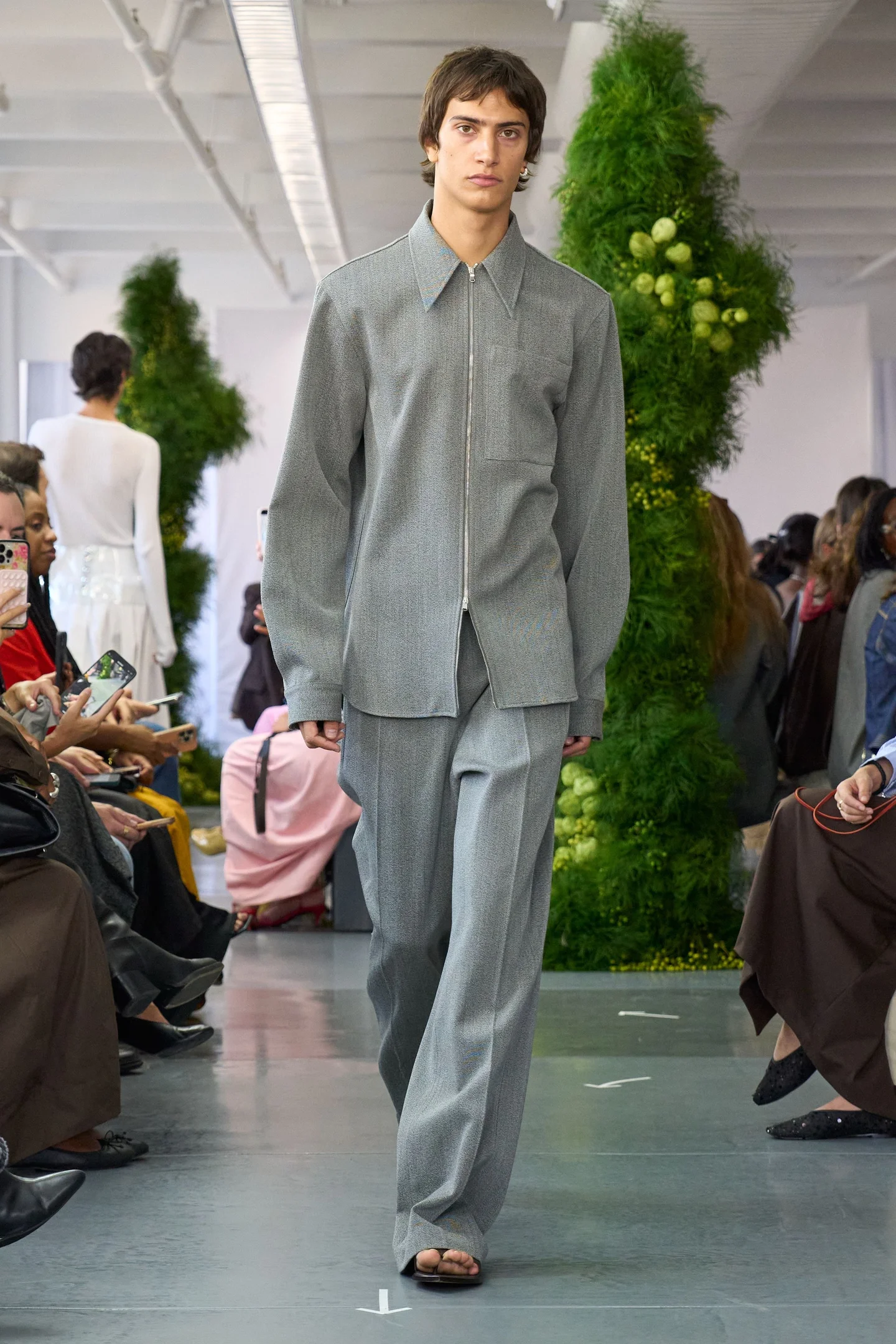 Modelo desfilando com conjunto de alfaiataria e chinelo de dedo na passarela da NYFW SS26