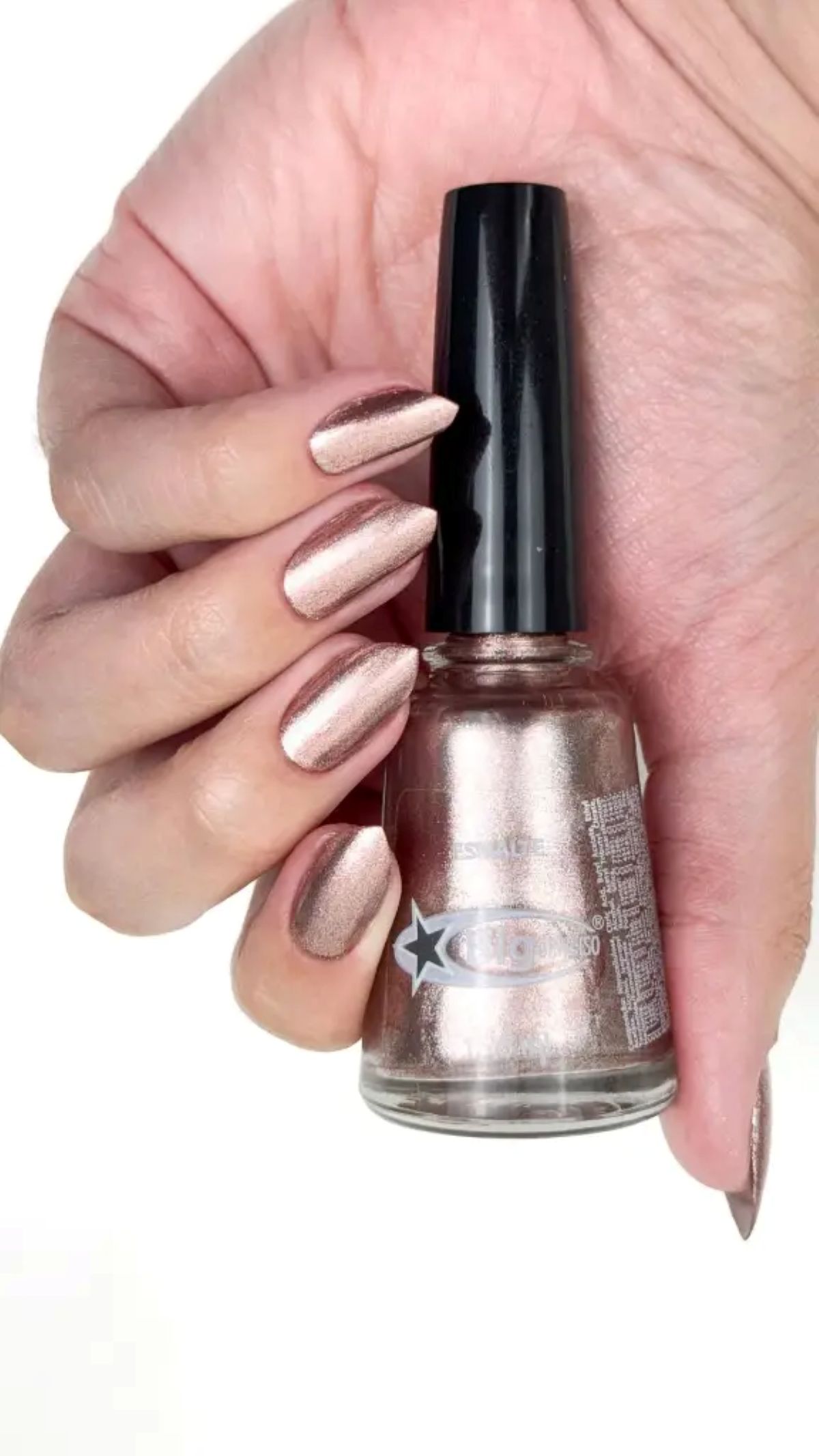 Esmalte metalizado rosé platinado nas unhas, segurando o frasco da marca Big Universo.