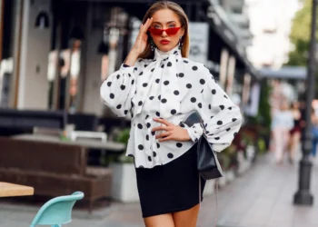 Mulher estilosa com blusa de poá e saia preta em look elegante na rua