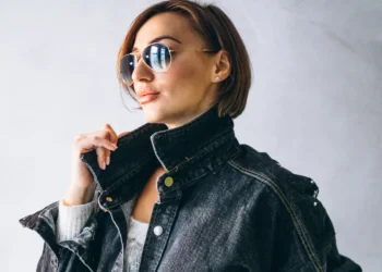 Mulher estilosa com jaqueta de gola alta jeans e óculos escuros.