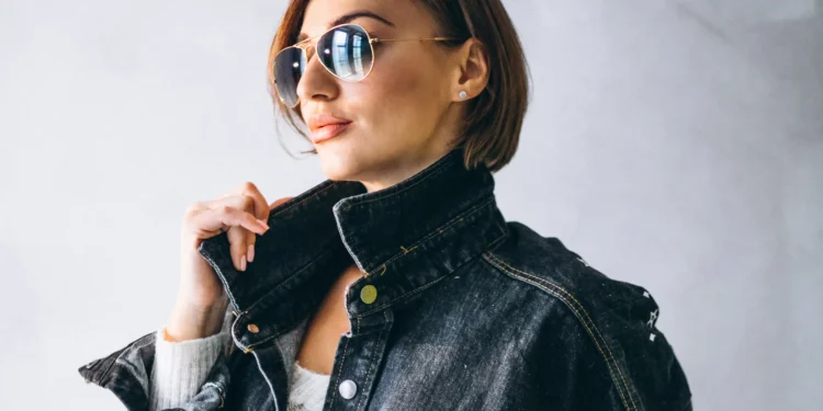 Mulher estilosa com jaqueta de gola alta jeans e óculos escuros.