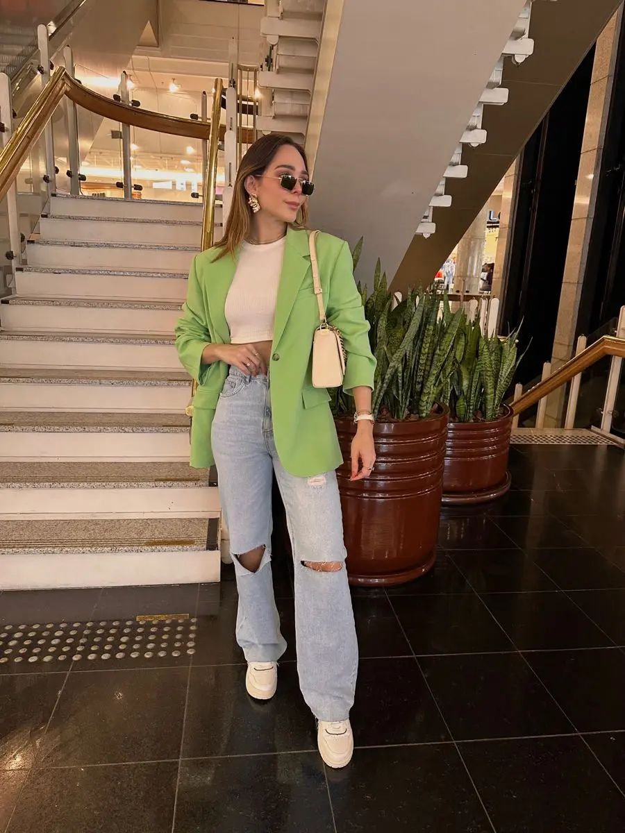 Look casual com blazer verde, calça jeans e tênis branco, perfeito para eventos descontraídos.