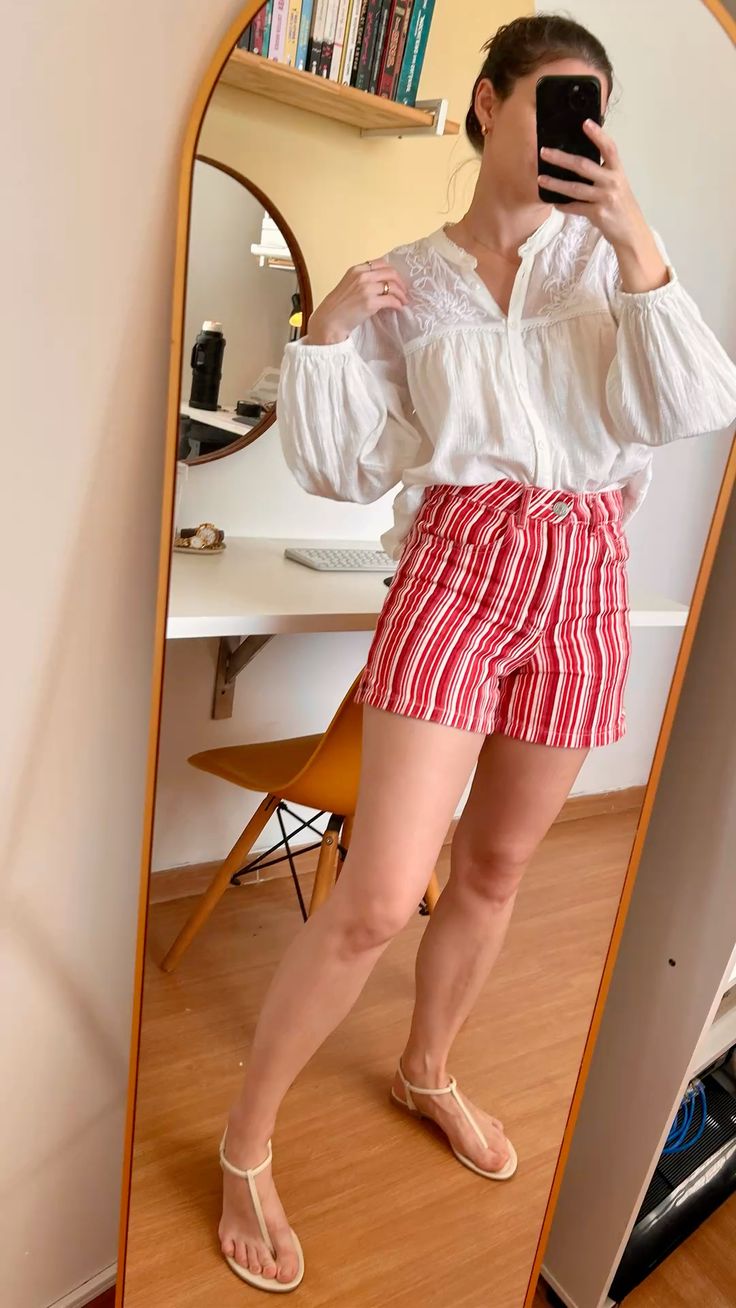 mulher usando shorts listrado em vermelho e branco e blusa de manga longa branca