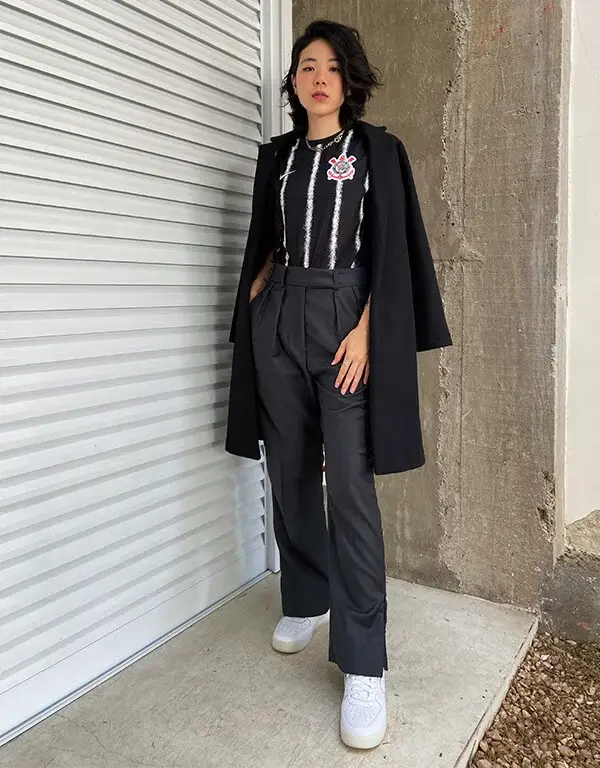 Mulher usando camisa de time com blazer preto e calça de alfaiataria