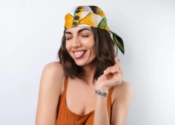 Mulher sorrindo com lenço colorido na cabeça, tendência para a primavera 2025.