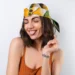 Mulher sorrindo com lenço colorido na cabeça, tendência para a primavera 2025.