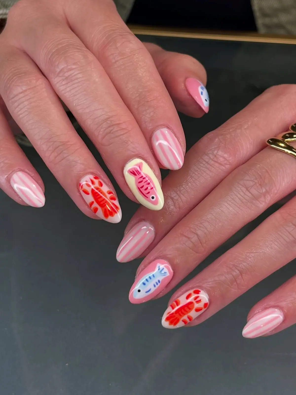 Unhas decoradas com estampas de peixe colorido, criando um visual divertido e único.
