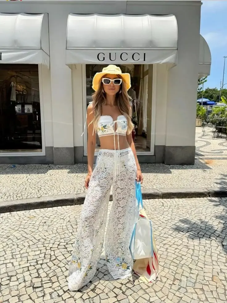 Look de verão com calça de renda e top cropped branco, ideal para eventos casuais.
