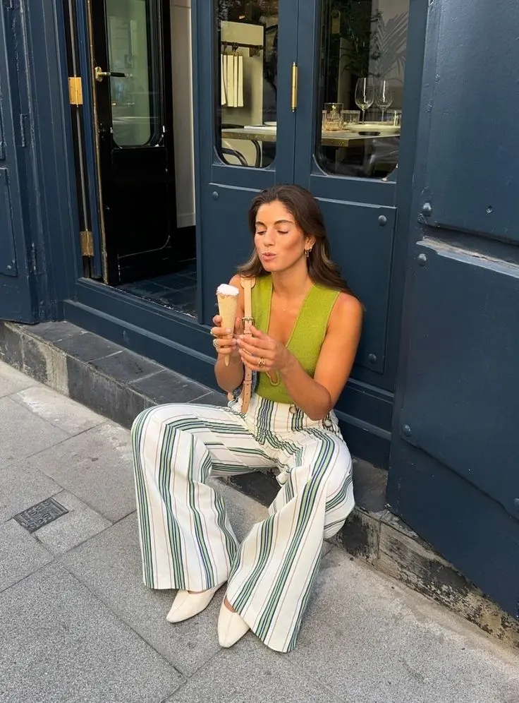 Mulher usando look casual com calça listrada verde, destacando estilo moderno e confortável.