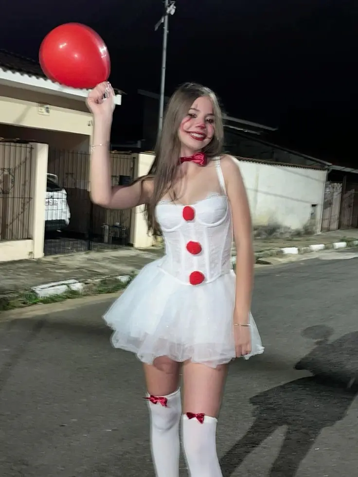Cosplay de palhaço inspirado em Pennywise, com vestido branco, laços vermelhos, balão vermelho e pompons.