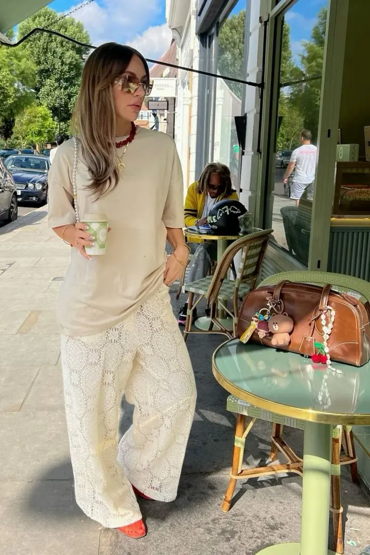 Mulher usando um look monocromático com calça de renda, camiseta oversized e acessórios modernos.