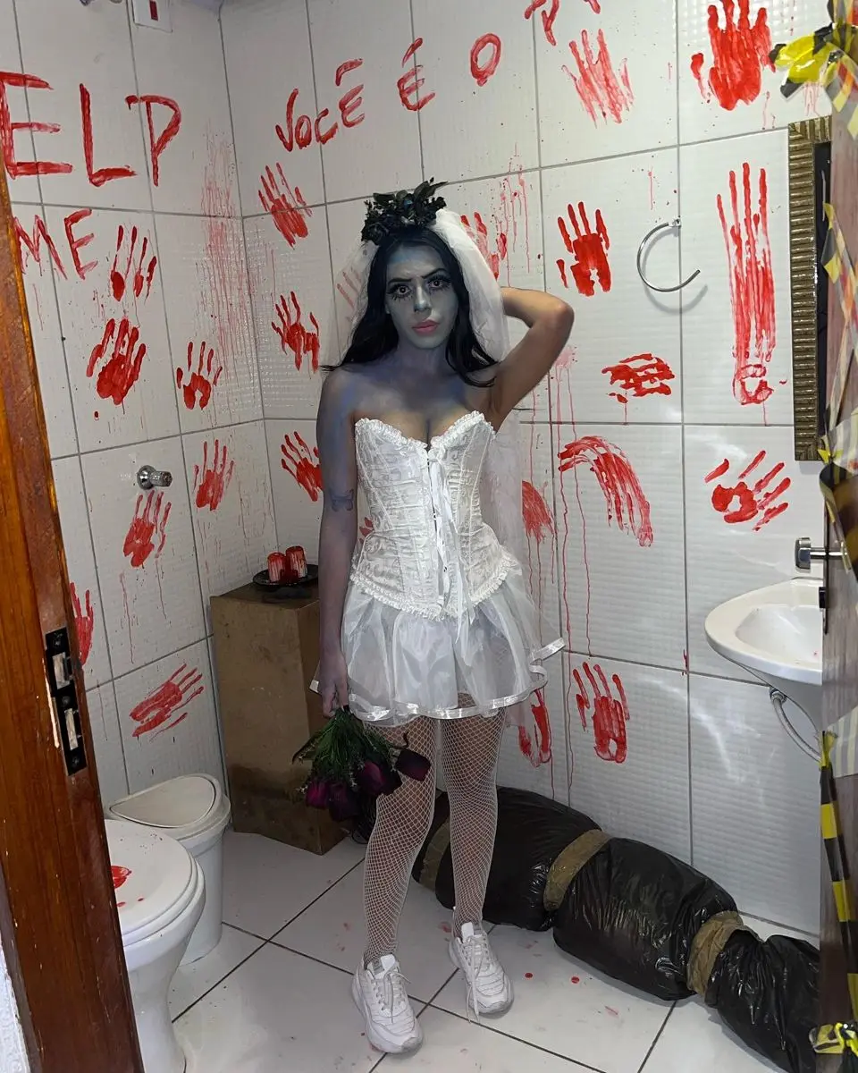 Mulher caracterizada como Noiva Cadáver, com maquiagem pálida e vestido branco.