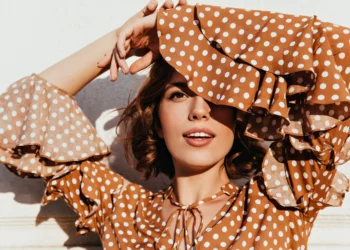 Modelo feminina usando vestido de poá marrom com detalhes modernos, exibindo estilo elegante na primavera.